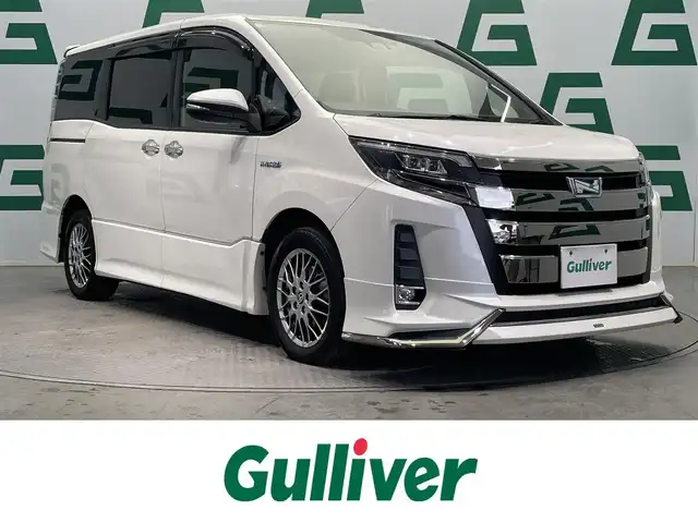 トヨタ ノア ハイブリッド Si ダブルバイビー 鹿児島県 2018(平30)年 8.6万km ホワイトパールクリスタルシャイン 禁煙車/トヨタセーフティセンスC/　・プリクラッシュセーフティ/　・レーンディバーチャーアラート/　・オートマチックハイビーム/先行車発進告知機能/クルーズコントロール(追従走行無し)/純正9型ナビ/　・Bluetooth/　・フルセグTV/　・CD/DVD/　・AM/FM/純正後席モニター/両側パワースライドドア/ETC/モデリスタエアロ/全席オートパワーウィンドウ/純正フロアマット/電動格納ミラー/ステアリングリモコン