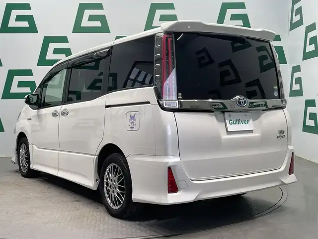 トヨタ ノア ハイブリッド Si ダブルバイビー 鹿児島県 2018(平30)年 8.6万km ホワイトパールクリスタルシャイン 禁煙車/トヨタセーフティセンスC/　・プリクラッシュセーフティ/　・レーンディバーチャーアラート/　・オートマチックハイビーム/先行車発進告知機能/クルーズコントロール(追従走行無し)/純正9型ナビ/　・Bluetooth/　・フルセグTV/　・CD/DVD/　・AM/FM/純正後席モニター/両側パワースライドドア/ETC/モデリスタエアロ/全席オートパワーウィンドウ/純正フロアマット/電動格納ミラー/ステアリングリモコン