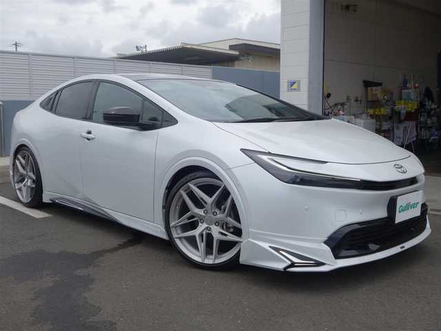 トヨタ プリウス Z 静岡県 2023(令5)年 0.7万km プラチナホワイトパールマイカ ワンオーナー・禁煙車/＜外装＞/モデリスタNEO ADVANCE STYLEエアロ/　フロントスポイラー/　サイドスカート/サイドガーニッシュ/　リヤスタイリングキット/　GRテールゲートスポイラー同色塗装/　フロント・リヤアーチ周り同色塗装/TEIN FREX車高調整キット/　アライメント調整済み/WORK グノーシス20インチAW/　タイヤ前後アゼニス225/35ZR20/パノラマルーフ・パワーバックドア/＜内装＞マチュアレッド色/12.3型ディスプレイオーディオプラス/コネクティッドナビ　フルセグ（TVキット）/パノラミックビューモニター/ビルトインETC2.0/純正デジタルインナーミラー/トヨタセーフティーセンス/　トヨタチームメイト/　メーカーオプション/　ドライブレコーダー前後方/　ブラインドスポットモニター/　安心降車アシスト+後方車両接近/　周辺車両接近時サポート/　後方車両への接近警報/　セカンダリーコリジョンブレーキ/ワイヤレス充電器/純正レクサスNX用シフトノブ/前席シートヒーター・ベンチレーション/アクセサリーコンセント/　AC100V 1500W/各種社外ピアノブラックパネル/純正フロアマット/　