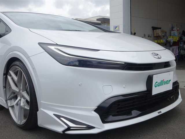 トヨタ プリウス Z 静岡県 2023(令5)年 0.7万km プラチナホワイトパールマイカ ワンオーナー・禁煙車/＜外装＞/モデリスタNEO ADVANCE STYLEエアロ/　フロントスポイラー/　サイドスカート/サイドガーニッシュ/　リヤスタイリングキット/　GRテールゲートスポイラー同色塗装/　フロント・リヤアーチ周り同色塗装/TEIN FREX車高調整キット/　アライメント調整済み/WORK グノーシス20インチAW/　タイヤ前後アゼニス225/35ZR20/パノラマルーフ・パワーバックドア/＜内装＞マチュアレッド色/12.3型ディスプレイオーディオプラス/コネクティッドナビ　フルセグ（TVキット）/パノラミックビューモニター/ビルトインETC2.0/純正デジタルインナーミラー/トヨタセーフティーセンス/　トヨタチームメイト/　メーカーオプション/　ドライブレコーダー前後方/　ブラインドスポットモニター/　安心降車アシスト+後方車両接近/　周辺車両接近時サポート/　後方車両への接近警報/　セカンダリーコリジョンブレーキ/ワイヤレス充電器/純正レクサスNX用シフトノブ/前席シートヒーター・ベンチレーション/アクセサリーコンセント/　AC100V 1500W/各種社外ピアノブラックパネル/純正フロアマット/　