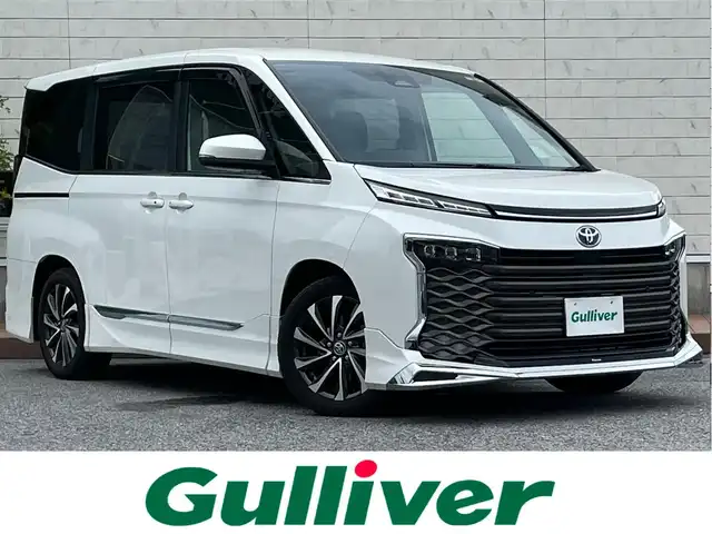 トヨタ ヴォクシー ハイブリッド S－Z 滋賀県 2022(令4)年 2万km ホワイトパールクリスタルシャイン モデリスタエアロ/12.3インチ有機ELフリップダウンモニター/10.5インチディスプレイオーディオ/（FM/AM/CD/DVD/フルセグ/Bluetooth/HDMI）/快適利便パッケージHigh/・ハンズフリーデュアルパワースライドドア/・パワーバックドア/・ステアリングヒーター/・後席シートヒーター/・ナノイーX/ETC2.0/前後ドライブレコーダー/バックカメラ/ＴｏｙｏｔａＳａｆｅｔｙＳｅｎｓｅ/・プリクラッシュブレーキアシスト	/・ブラインドスポットモニター（ＢＳＭ）/・安心降車アシスト（ドアオープン制御付）（ＳＥＡ）/・パーキングサポートブレーキ（後方接近車両）/・パーキングサポートブレーキ（後方歩行者）/・レーンキープアシスト	/・レーダークルーズコントロール/・標識検知機能/オットマン/運転席・助手席シートヒーター/キャプテンシートシートヒーター/電動格納ミラー/電子パーキング/ブレーキホールド/革巻きステアリング/ステアリングスイッチ/オートライト/LEDヘッドライト/オートマチックハイビーム/プッシュスタート/スマートキー/純正フロアマット