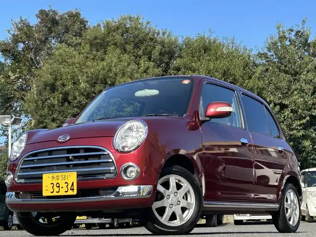 ダイハツ ミラ ジーノ プレミアムX 東京都 2008(平20)年 8.8万km ルージュレッドクリスタルメタリック フロントフォグランプ/MOMO製本木製ステアリングホイール/木目調シフトノブ/タン革/スエード調ファブリックコンビシート/carrozzeriaオーディオ（MVH-5600）/・Bluetoothオーディオ/AUX/FM/AM/ETC/取扱説明書/保証書