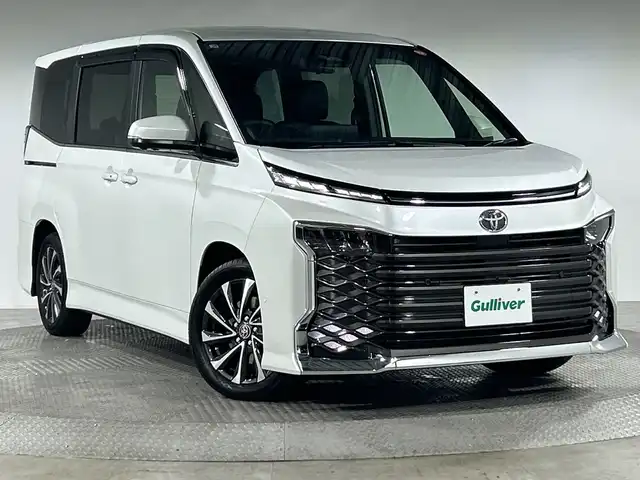 トヨタ ヴォクシー ハイブリッド S－Z 神奈川県 2025(令7)年 0.1千km プラチナホワイトパールマイカ 登録済未使用車/ディスプレイオーディオプラス/純正10.5型ディスプレーオーディオ/メモリーナビ/フルセグ　CD DVD USB　HDMI　Bluetooth　MiraCast　ETC2.0/バックカメラ/両側電動スライドドア/パワーバックドア/トヨタチームメイト/快適利便パッケージ/ユニバーサルステップ/セーフティセンス/プリクラッシュセーフティ/レーンディパーチャーアラート/オートマチックハイビーム/ドライバー異常時対応システム/発進遅れ告知機能/レーントレーシングアシスト/レーダークルーズコントロール/ロードサインアシスト/パーキングサポートブレーキ/車両接近通報装置/プロアクティブドライビングアシスト/カラーヘッドアップディスプレイ/デジタルインナーミラー/ステアリングヒーター/前席/2列目左右シートヒーター/ステアリングヒーター/合皮/ファブリックコンビシート/革巻きステアリング/AC100V/SOSコール/プッシュスタート/スマートキー/LEDヘッドライト/オートライト/純正17インチアルミホイール/純正サイド/リアスポイラー