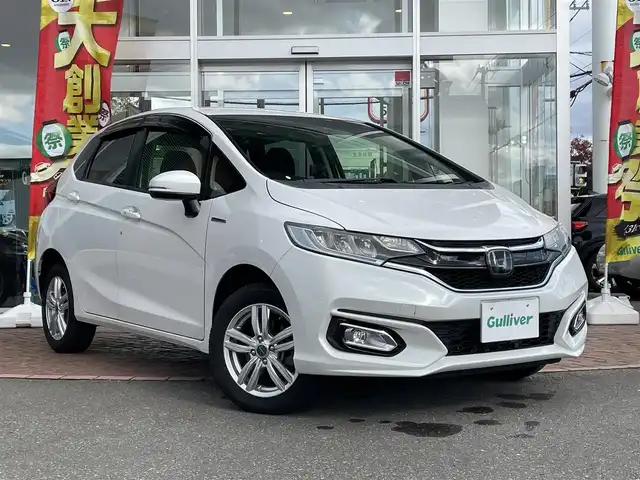 ホンダ フィット ハイブリット L ホンダセンシング 道央・札幌 2018(平30)年 4.6万km プラチナホワイトパール 登録時走行距離46031km/ワンオーナー/　４　W　D　/ホンダセンシング/寒冷地仕様/社外メモリナビ（CD/DVD/FM/AM/SD/BT)/フルセグ（走行中視聴可能）/バックカメラ/ウィンカーミラー/クルーズコントロール（追従走行あり）/ドアバイザー/プッシュスタート/ビルトインETC/スペアキー×１/純正エンジンスターター/USB入力端子/ドライブレコーダー（前方）/ハーフレザーシート/純正フロアマット/横滑り防止装置/盗難防止装置/衝突軽減ブレーキ/レーンキープアシスト/オートライト/フォグランプ/フロントデアイサースイッチ/ECONスイッチ/電動格納ミラー/バニティミラー/ワイパー間欠時間コントローラー/Sモードスイッチ/積込冬タイヤ（純正WCP/185/60/R15/18年製/溝4mm）