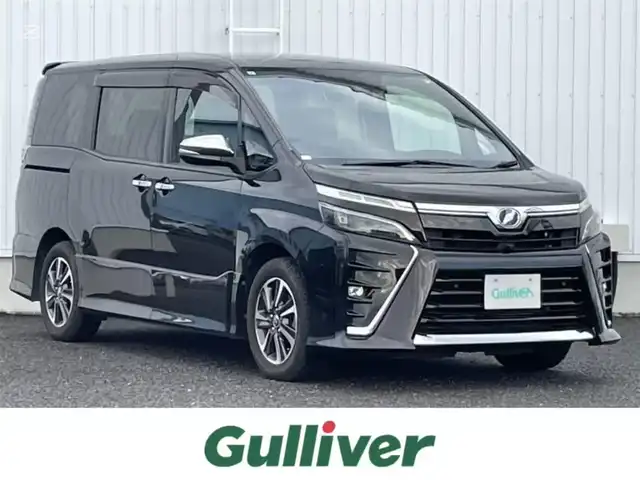 トヨタ ヴォクシー ZS 煌Ⅱ 熊本県 2019(令1)年 6.6万km イナズマスパーキングブラックガラスフレーク 社外ナビ/・BT/CD/DVD/SD/USB/AM/FM/・フルセグ/フリップダウンモニター/バックカメラ/前後ドラレコ/両側パワースライドドア/トヨタセーフティーセンス/ビルトインETC/革巻きステアリング/・ステアリングリモコン/クルーズコントロール/MTモード付AT/プッシュスタート/・スマートキー/・スペアキー×１/アイドリングストップ/純正AW/純正ドアバイザー/純正フロアマット/電動格納ミラー/・ミラーウィンカー/ロールサンシェード