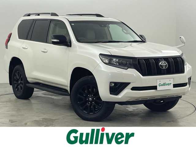 トヨタ ランドクルーザー プラド TX Lパッケージ マットブラED 福岡県 2023(令5)年 2.5万km ホワイトパールクリスタルシャイン ワンオーナー　/７人乗り　/サンルーフ　/ルーフレール　/社外８型ディスプレイオーディオ　/バックカメラ　/ビルトインＥＴＣ　/前方ドライブレコーダー　/レーダークルーズコントロール　/コーナーセンサー　/衝突被害軽減ブレーキ　/レーンキープ　/アクセル踏み間違い防止　/先行車発進お知らせ　/ＭＴモード付き　/寒冷地仕様　/ベージュ本革シート　/パワーシート　/ベンチレーション／シートヒーター　/ＬＥＤヘッドライト