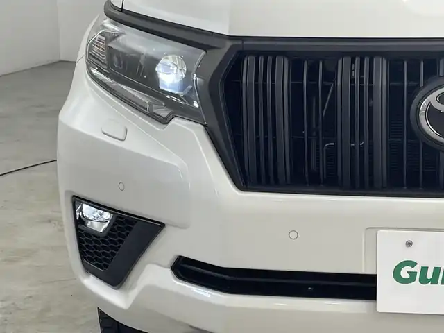 トヨタ ランドクルーザー プラド TX Lパッケージ マットブラED 福岡県 2023(令5)年 2.5万km ホワイトパールクリスタルシャイン ワンオーナー　/７人乗り　/サンルーフ　/ルーフレール　/社外８型ディスプレイオーディオ　/バックカメラ　/ビルトインＥＴＣ　/前方ドライブレコーダー　/レーダークルーズコントロール　/コーナーセンサー　/衝突被害軽減ブレーキ　/レーンキープ　/アクセル踏み間違い防止　/先行車発進お知らせ　/ＭＴモード付き　/寒冷地仕様　/ベージュ本革シート　/パワーシート　/ベンチレーション／シートヒーター　/ＬＥＤヘッドライト