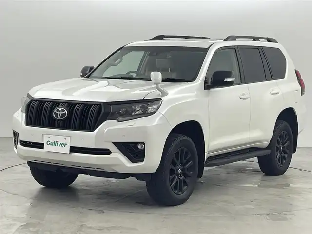 トヨタ ランドクルーザー プラド TX Lパッケージ マットブラED 福岡県 2023(令5)年 2.5万km ホワイトパールクリスタルシャイン ワンオーナー　/７人乗り　/サンルーフ　/ルーフレール　/社外８型ディスプレイオーディオ　/バックカメラ　/ビルトインＥＴＣ　/前方ドライブレコーダー　/レーダークルーズコントロール　/コーナーセンサー　/衝突被害軽減ブレーキ　/レーンキープ　/アクセル踏み間違い防止　/先行車発進お知らせ　/ＭＴモード付き　/寒冷地仕様　/ベージュ本革シート　/パワーシート　/ベンチレーション／シートヒーター　/ＬＥＤヘッドライト