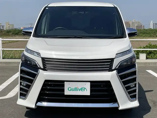 トヨタ ヴォクシー ZS 煌Ⅱ 佐賀県 2019(令1)年 4.9万km ホワイトパールクリスタルシャイン SiLK Blazeリアスポイラー・リアアンダー/社外フロントグリル/純正9インチナビ/・フルセグTV/CD/SD/Bluetooth/フリップダウンモニター/ドラレコ付きデジタルインナーミラー/バックカメラ/両側パワースライドドア/後席用サイドサンシェード/ISOFIX対応/ビルトインETC/革巻きステアリング/ステアリングリモコン/クルーズコントロール/レーンディパーチャーアラート/プリクラッシュブレーキ/先行車発進お知らせ機能/クリアランスソナー/ウィンカーミラー/純正LEDヘッドライト/純正LEDフォグライト/純正1６インチアルミ/スペアキー１本