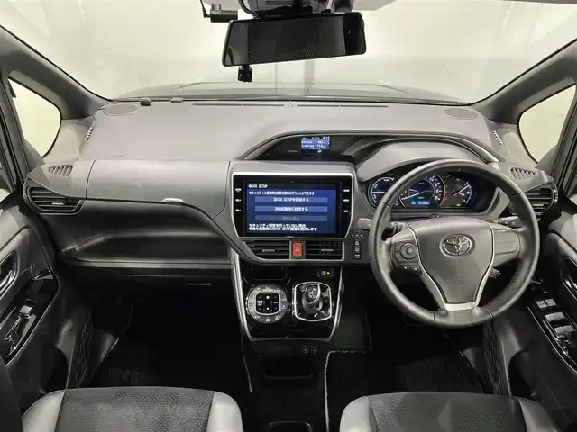 トヨタ ヴォクシー ハイブリッド ZS 煌Ⅲ 愛知県 2021(令3)年 2.3万km ブラック 純正10インチメーカーナビ/衝突軽減ブレーキ/両側電動スライドドア/ビルトインETC2.0/シートヒーター/LEDヘッドライト/バックカメラ/クルーズコントロール/フルセグTV/Bluetooth/コーナーセンサー/レーンキープアシスト/オートハイビーム/プッシュスタート/スマートキー/スペアキー/CD/DVD再生/ミュージックサーバー/純正フロアマット/純正アルミホイール/オートライト/禁煙車/後期モデル/特別仕様車/ウィンカーミラー/電動格納ミラー/フォグランプ/シートバックテーブル/ステアリングリモコン/Wエアコン/トラクションコントロールシステム/パーキングサポートブレーキ/先行車発進告知