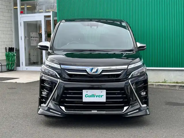 トヨタ ヴォクシー ハイブリッド ZS 煌Ⅱ 宮城県 2019(平31)年 13.6万km イナズマスパーキングブラックガラスフレーク TRDエアロ（F/S/R）/セーフティセンス/・プリクラッシュセーフティ/・レーンディパーチャーアラート/・オートマチックハイビーム/・先行車発進お知らせ機能/インテリジェントクリアランスソナー/パーキングサポートブレーキ/社外10.2インチフリップダウンモニター（TMX-R3300）/社外9インチナビ（AVN-ZX03i）/・CD/DVD/・Bluetooth/・フルセグTV/バックカメラ/ETC/両側パワースライドドア/シートヒーター/革巻きステアリング/クルーズコントロール/ステアリングスイッチ/LEDヘッドランプ/フォグランプ/オートライト/スマートキー＆プッシュスタート/電動格納ミラー/純正16インチAW/純正ドアバイザー/フロアマット/Wエアバッグ