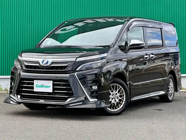 トヨタ ヴォクシー ハイブリッド ZS 煌Ⅱ 宮城県 2019(平31)年 13.6万km イナズマスパーキングブラックガラスフレーク TRDエアロ（F/S/R）/セーフティセンス/・プリクラッシュセーフティ/・レーンディパーチャーアラート/・オートマチックハイビーム/・先行車発進お知らせ機能/インテリジェントクリアランスソナー/パーキングサポートブレーキ/社外10.2インチフリップダウンモニター（TMX-R3300）/社外9インチナビ（AVN-ZX03i）/・CD/DVD/・Bluetooth/・フルセグTV/バックカメラ/ETC/両側パワースライドドア/シートヒーター/革巻きステアリング/クルーズコントロール/ステアリングスイッチ/LEDヘッドランプ/フォグランプ/オートライト/スマートキー＆プッシュスタート/電動格納ミラー/純正16インチAW/純正ドアバイザー/フロアマット/Wエアバッグ