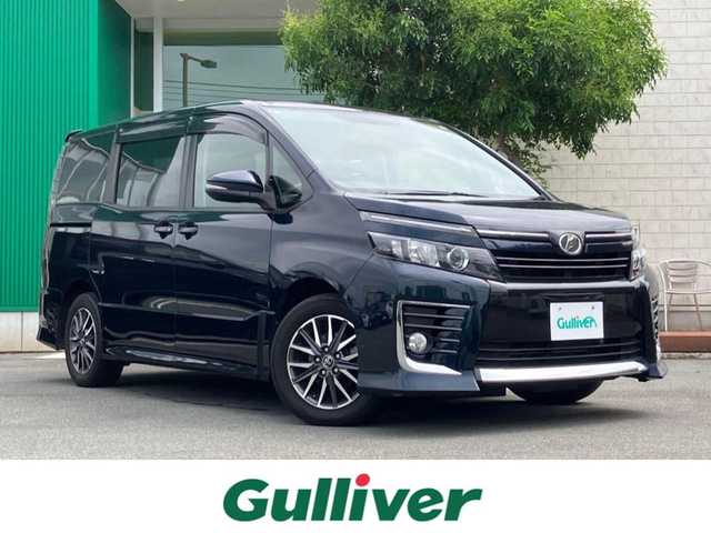 トヨタ ヴォクシー ZS 静岡県 2014(平26)年 4.8万km ブラッキッシュアゲハガラスフレーク エンジンスタートボタン/パワーステアリング/パワーウィンドウ/アイドリングストップ/スマートキー/ダブルオートエアコン/Bluetooth接続/11型後席用モニター/CDチェンジャー/ETC/バックカメラ/SDミュージックサーバー/フルセグTV/純正SDナビ/3列シート/ウォークスルー/純正フロアマット/両側パワースライドドア/純正アルミホイール/ABS/横滑り防止装置/オートライト/LEDヘッドライト/ダブルエアバック