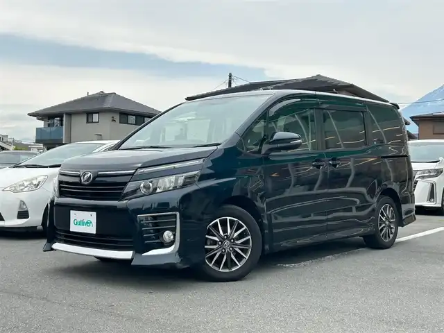 トヨタ ヴォクシー ZS 静岡県 2014(平26)年 4.8万km ブラッキッシュアゲハガラスフレーク エンジンスタートボタン/パワーステアリング/パワーウィンドウ/アイドリングストップ/スマートキー/ダブルオートエアコン/Bluetooth接続/11型後席用モニター/CDチェンジャー/ETC/バックカメラ/SDミュージックサーバー/フルセグTV/純正SDナビ/3列シート/ウォークスルー/純正フロアマット/両側パワースライドドア/純正アルミホイール/ABS/横滑り防止装置/オートライト/LEDヘッドライト/ダブルエアバック