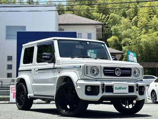 スズキ ジムニー シエラ JC 熊本県 2022(令4)年 2.4万km ピュアホワイトP ワンオーナー/ダムドリトルGスタンダードコンプリートカー/・フロントグリル/・フロントバンパー/・オーバーフェンダー＆アルミステップサイドモール/・スペアタイヤハードカバー/・G15エンブレム/社外ナビ（CN-F1X10BHD）/【10V型有機ELディスプレイ/フルセグTV/BT】/バックカメラ/社外デジタルインナーミラー/デュアルセンサーブレーキサポート/車線逸脱警報システム/クルーズコントロール/社外ダウンサス/社外18インチアルミホイール（純正品積込有）/革巻きツートンステアリング（純正品積込有）/ビルトインETC/ドライブレコーダー（前後）/LEDオートライト/レザー調シートカバー/シートヒーター/プッシュスタート/スマートキー/保証書/取扱説明書