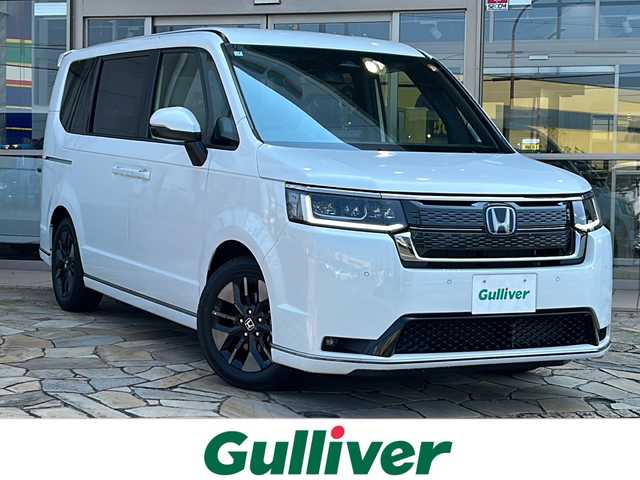 ホンダ ステップワゴン スパーダ eHEV 静岡県 2025(令7)年 0.1千km プラチナホワイトパール 純正ナビ/・CD/DVD/・RADIO/・フルセグTV/・Music Rack/・SD/・USB/・BTA/ホンダセンシング/・衝突軽減ブレーキ（CMBS）/・先行車発進お知らせ機能/・歩行者事故低減ステアリング/・路外逸脱抑制機能/・標識認識機能/・渋滞追従機能付アダプティブクルーズコントロール（ACC）/・車線維持支援システム（LKAS）/・トラフィックジャムアシスト（渋滞運転支援機能）/・ブラインドスポットインフォメーション/・誤発進抑制機能/・後方誤発進抑制機能/・近距離衝突軽減ブレーキ/・急アクセル抑制機能/・パーキングセンサーシステム/・オートハイビーム/主要装備/・両側パワースライドドア/・バックカメラ/・電動パーキング/・パドルシフト/・パワーバックドア/・運転席+助手席シートヒーター/・リアオートエアコン/・減速セレクター/・全列ＵＳＢチャージャー/・２列目オットマン/・SPADA専用16インチアルミ