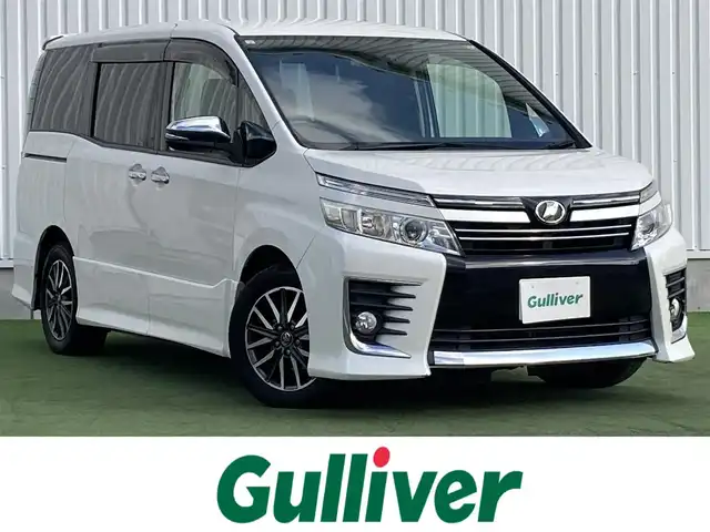 トヨタ ヴォクシー ZS 煌 香川県 2015(平27)年 12万km ホワイトパールクリスタルシャイン 登録時走行距離：119662km/アルパイン9型SDナビ/　CD DVD BT フルセグTV/バックカメラ/アルパイン10.1型フリップダウンモニター/両側パワースライドドア/LEDヘッドライト/オートライト/フォグランプ/MTモード付AT/ビルトインETC/ドライブレコーダー/ロールサンシェード/ISOFIX/ウォークスルー/革巻きステアリング/ステアリングスイッチ/プッシュスタート/スマートキー/スペアキー