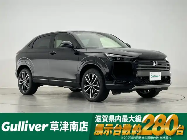ホンダ ヴェゼル ハイブリッド e:HEV Z 滋賀県 2025(令7)年 0.1千km クリスタルブラックパール 純正9インチナビ/【Bluetooth/USB/Apple CarPlay/Android Auto】/バックカメラ/ハーフレザーシート/ホンダセンシング/・衝突軽減ブレーキ（CMBS）/・先行車発進お知らせ機能/・歩行者事故低減ステアリング/・路外逸脱抑制機能/・標識認識機能/・渋滞追従機能付アダプティブクルーズコントロール/・車線維持支援システム（LKAS）/・トラフィックジャムアシスト（渋滞運転支援機能）/・ブラインドスポットインフォメーション/・誤発進抑制機能/・後方誤発進抑制機能/・近距離衝突軽減ブレーキ/・急アクセル抑制機能/・パーキングセンサーシステム/・後退出庫サポート/・オートハイビーム/・アダプティブドライビングビーム/LEDヘッドライト/クリアランスソナー/シートヒーター/ステアリングヒーター/ヒルディセントコントロール/ワイヤレス充電/ビルトインETC2.0/衝突軽減ブレーキ/パワーバックドア/電動パーキングブレーキ/オートブレーキホールド/純正フロアマット