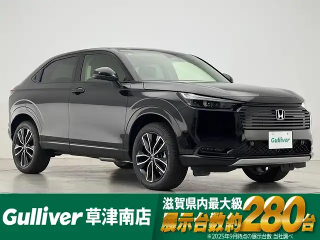 ホンダ ヴェゼル ハイブリッド e:HEV Z 滋賀県 2025(令7)年 0.1千km クリスタルブラックパール 純正9インチナビ/【Bluetooth/USB/Apple CarPlay/Android Auto】/バックカメラ/ハーフレザーシート/ホンダセンシング/・衝突軽減ブレーキ（CMBS）/・先行車発進お知らせ機能/・歩行者事故低減ステアリング/・路外逸脱抑制機能/・標識認識機能/・渋滞追従機能付アダプティブクルーズコントロール/・車線維持支援システム（LKAS）/・トラフィックジャムアシスト（渋滞運転支援機能）/・ブラインドスポットインフォメーション/・誤発進抑制機能/・後方誤発進抑制機能/・近距離衝突軽減ブレーキ/・急アクセル抑制機能/・パーキングセンサーシステム/・後退出庫サポート/・オートハイビーム/・アダプティブドライビングビーム/LEDヘッドライト/クリアランスソナー/シートヒーター/ステアリングヒーター/ヒルディセントコントロール/ワイヤレス充電/ビルトインETC2.0/衝突軽減ブレーキ/パワーバックドア/電動パーキングブレーキ/オートブレーキホールド/純正フロアマット