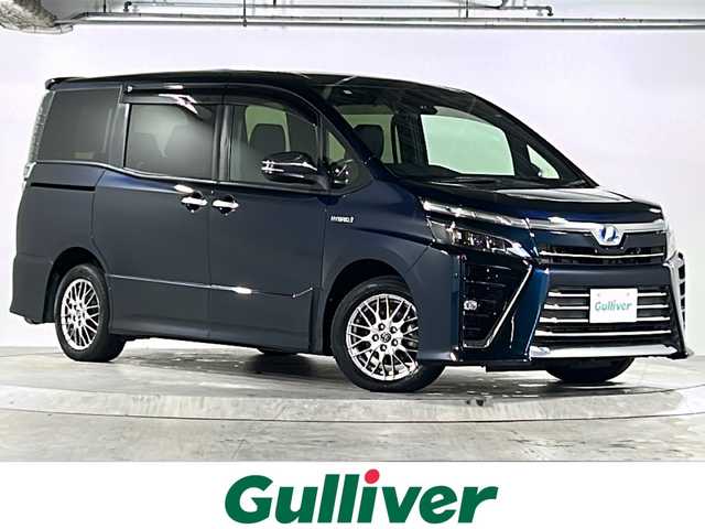 トヨタ ヴォクシー ハイブリッド ZS 煌 広島県 2018(平30)年 6.4万km ブラッキッシュアゲハガラスフレーク 禁煙車/トヨタセーフティセンス/・プリクラッシュセーフティ/・先行車発進告知/・オートマチックハイビーム/・LDA/クルーズコントロール/コーナーセンサー/純正10インチナビ（NSZN-Z66T）/・CD/DVD/フルセグ/Bluetooth/SD/REC/純正フリップダウンモニター（V12T-R66C）/バックカメラ/両側パワースライドドア/革巻きステアリング/オートライト/ステアリングスイッチ/D/Nシートヒーター/LEDヘッドライト/フォグランプ/サンシェード/ビルトインETC/純正フロアマット/純正ドアバイザー/スマートキー/プッシュスタート/スペアキー/純正16インチアルミホイール