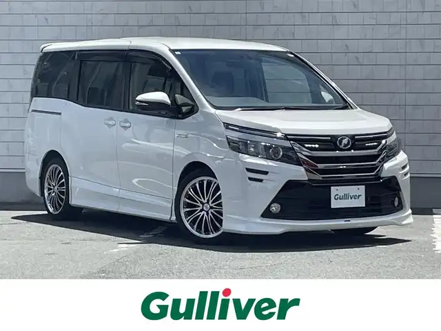 トヨタ ヴォクシー ハイブリッド V 愛知県 2014(平26)年 6万km ホワイトパールクリスタルシャイン ローダウンスプリング/純正9型ナビ/　(Bluetooth/CD/DVD)/フルセグTV/両側パワースライドドア/バックモニター/ビルトインETC/純正11型後席ディスプレイ/クルーズコントロール/S-VSC/LEDヘッドランプ/オートライト/デュアルオートエアコン/本革巻きステアリング/ステアリングスイッチ/前席快適温熱シート/2列目キャプテンシート/2列目サイドテーブル/ロクサーニEX18インチアルミホイール/スマートエントリー/プッシュスタートシステム/禁煙車