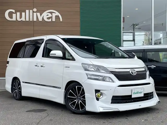 トヨタ ヴェルファイア ハイブリット ZR Gエディション 道央・札幌 2013(平25)年 9.4万km ホワイトパールクリスタルシャイン 登録時走行距離 93155km/　4　W　D　/フロントモデリスタエアロ/ローダウン/純正メーカーOPナビ/(AM/FM/CD/DVD/BT)/フルセグTV/バックカメラ/プレミアムサウンド/純正フリップダウンモニター/両側パワースライドドア/パワーバックドア/ビルトインETC/黒革シート/助手席オットマン/2列目キャプテンシート/社外ウィンカーミラー/社外フロントグリル/ウッドコンビステアリング/社外レーダー/純正サスペンション積込/社外テール積込(動作未確認)/純正AW付冬タイヤ積込/215/65R16 2023年製 7mm