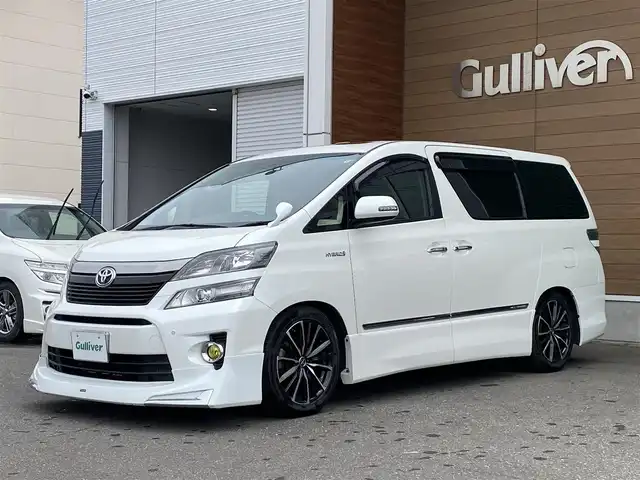 トヨタ ヴェルファイア ハイブリット ZR Gエディション 道央・札幌 2013(平25)年 9.4万km ホワイトパールクリスタルシャイン 登録時走行距離 93155km/　4　W　D　/フロントモデリスタエアロ/ローダウン/純正メーカーOPナビ/(AM/FM/CD/DVD/BT)/フルセグTV/バックカメラ/プレミアムサウンド/純正フリップダウンモニター/両側パワースライドドア/パワーバックドア/ビルトインETC/黒革シート/助手席オットマン/2列目キャプテンシート/社外ウィンカーミラー/社外フロントグリル/ウッドコンビステアリング/社外レーダー/純正サスペンション積込/社外テール積込(動作未確認)/純正AW付冬タイヤ積込/215/65R16 2023年製 7mm