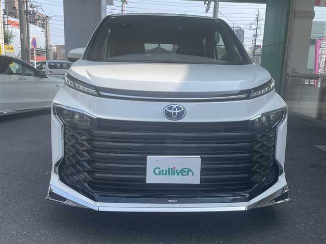 トヨタ ヴォクシー ハイブリッド S－Z 愛知県 2023(令5)年 1万km ホワイトパールクリスタルシャイン モデリスタエアロ/・フロント／サイド／リアアンダー/快適利便パッケージHifh/・ハンズフリー両側パワースライドドア/・ハンズフリーパワーバックドア/・2列目シートヒーター/・2列目オットマン/・ステアリングヒーター/・ナノイーX/ドライビングサポートパッケージ/・デジタルインナーミラー/・ヘッドアップディスプレイ/純正10.5型ディスプレイオーディオプラス/・車載メモリーナビ／DVD／Bluetooth／地デジTV/・Apple Car Play／Android Auto/・USB／HDMI/・ビルトインETC2.0/純正14型有機ELフリップダウンモニター/LEDヘッドライト＆クリアランスランプ/合皮＆ファブリックコンビシート/前席2列目シートヒーター/2列目充電用USBタイプC端子/ラゲッジルームアクセサリーコンセント/純正17インチAW/スマートキー