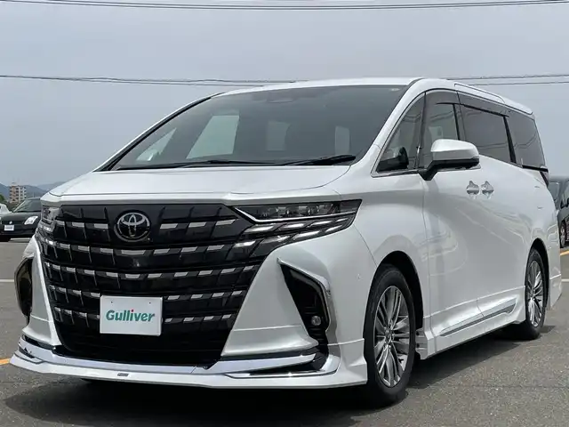 トヨタ アルファードハイブリット Z 佐賀県 2024(令6)年 0.9万km プラチナホワイトパールマイカ ワンオーナー/モデリスタエアロ【F/S/R】/左右独立ムーンルーフ/純正14型ディスプレイオーディオ/・HDMI/BT/AM/FM/フルセグTV/・Apple Car Play/Android Auto/パノラミックビューモニター/純正14型リヤシートエンターテインメントシステム/ビルトインETC2.0/純正前後ドライブレコーダー/黒革シート/・DN、セカンド席パワーシート/・DNセカンド席シートヒーター/ベンチレーション/・マイコンプリセットドライビングポジションシステム/・オットマン/革巻きステアリング【木目調】/・ステアリングヒーター/・パドルシフト/両側パワースライドドア/パワーバックドア/デジタルインナーミラー/カラーヘッドアップディスプレイ/後席用パワーサイドサンシェード/電動パーキングブレーキ/アクセサリーコンセント/置くだけ充電/純正18インチアルミホイール/3眼LEDヘッドランプ/アダプティブハイビームシステム/Toyota Safety Sence/・PCS/LTA/FCTA/・レーダークルーズコントロール/・パーキングサポートブレーキ/・ブラインドスポットモニター/・Advanced Park