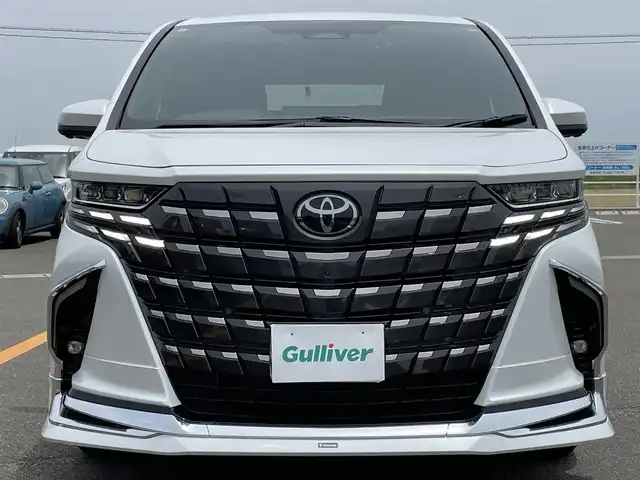 トヨタ アルファードハイブリット Z 佐賀県 2024(令6)年 0.9万km プラチナホワイトパールマイカ ワンオーナー/モデリスタエアロ【F/S/R】/左右独立ムーンルーフ/純正14型ディスプレイオーディオ/・HDMI/BT/AM/FM/フルセグTV/・Apple Car Play/Android Auto/パノラミックビューモニター/純正14型リヤシートエンターテインメントシステム/ビルトインETC2.0/純正前後ドライブレコーダー/黒革シート/・DN、セカンド席パワーシート/・DNセカンド席シートヒーター/ベンチレーション/・マイコンプリセットドライビングポジションシステム/・オットマン/革巻きステアリング【木目調】/・ステアリングヒーター/・パドルシフト/両側パワースライドドア/パワーバックドア/デジタルインナーミラー/カラーヘッドアップディスプレイ/後席用パワーサイドサンシェード/電動パーキングブレーキ/アクセサリーコンセント/置くだけ充電/純正18インチアルミホイール/3眼LEDヘッドランプ/アダプティブハイビームシステム/Toyota Safety Sence/・PCS/LTA/FCTA/・レーダークルーズコントロール/・パーキングサポートブレーキ/・ブラインドスポットモニター/・Advanced Park