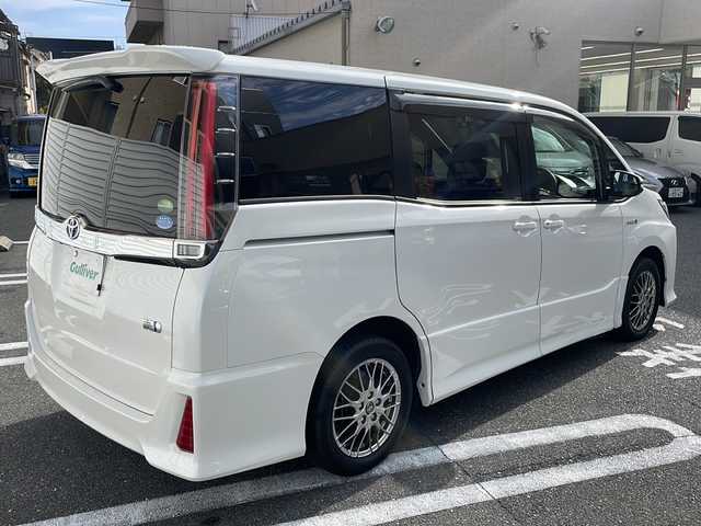 トヨタ ノア ハイブリッド Si 広島県 2017(平29)年 3.5万km ホワイトパールクリスタルシャイン 純正9インチナビ/(フルセグTV/CD/DVD/BT/AM/FM)/フリップダウンモニター/バックカメラ/衝突被害軽減システム/車線逸脱警報/クルーズコントロール/横滑り防止装置/ETC/アイドリングストップ/LEDヘッドライト/フォグランプ/オートライト/ウィンカーミラー/電動格納ミラー/純正１６インチAW/シートヒーター/シートリフター/プッシュスタート/スマートキー/フロアマット/ドアバイザー/スペアキー/取扱説明書/保証書