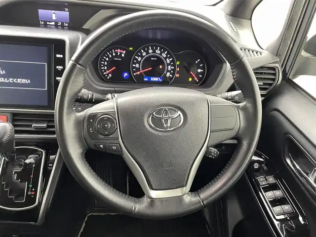 トヨタ ヴォクシー ZS 煌 熊本県 2018(平30)年 7万km ブラッキッシュアゲハガラスフレーク 純正10インチナビ（ＣＤ・ＤＶＤ・フルセグ・ＢＴ・ＳＤ・HDMI）/純正フリップダウンモニター/バックカメラ　/社外前後ドライブレコーダー　/ビルトインＥＴＣ　/両側パワースライドドア　/トヨタセーフティーセンス/・プリクラッシュセーフティ/・先行車発進お知らせ機能/・レーンキープアシスト/・クルーズコントロール/・レーンディパーチャーアラート/・オートマチックハイビーム/横滑り防止/アイドリングストップ/純正フロアマット/純正１６インチAW/オートライト/LEDヘッドライト/フォグライト/スマートキー/プッシュスタート