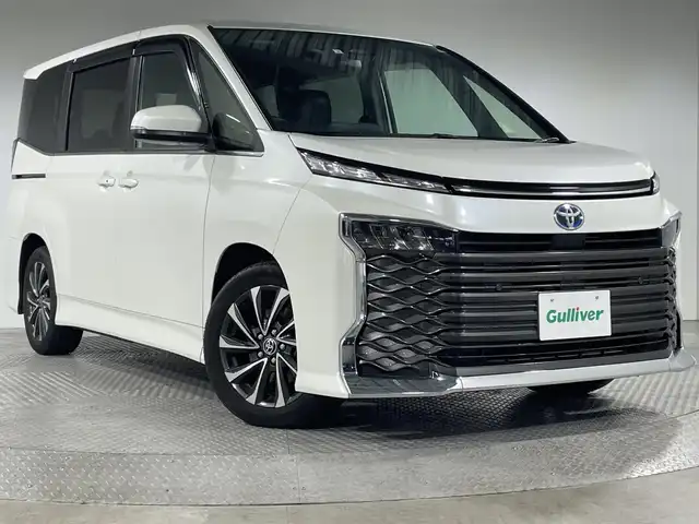 トヨタ ヴォクシー ハイブリッド S－Z 神奈川県 2023(令5)年 2万km ホワイトパールクリスタルシャイン ディスプレイオーディオプラス/コネクティッド対応10.5型ディスプレイオーディオ/車載メモリーナビ/純正後席モニター【V14T-R72R】/DVD CD　AM FM フルセグ　USB　HDMI　Applecarplay　Androidauto　Bluetooth　先読みエコドライブ　ETC2.0ユニット/ブラインドスポットモニター/両側電動スライドドア/セーフティセンス/安心降車アシスト/アドバンストドライブ/緊急時操舵支援/フロントトラフィックアラート/レーンチェンジアシスト/パーキングサポートブレーキ/プリクラッシュセーフティ/レーントレーシングアシスト/レーンディバーチャーアラート/レーダークルーズコントロール/オートマチックハイビーム/オードサインアシスト/ドライバー異常対応システム/プロアクティブドライビングアシスト/発進遅れ告知機能/パーキングサポートブレーキ/車両接近通報装置/フリーストップバックドア【イージークローザー】/革巻きステアリング【スイッチ】/合皮コンビシート/前席快適温熱シート/プッシュスタート/スマートキー/LEDヘッドランプ/純正17インチアルミホイール