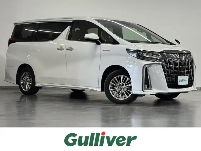 トヨタ アルファードハイブリット S タイプゴールド 三重県 2020(令2)年 6.4万km ホワイトパールクリスタルシャイン ハイブリッド/E-Four（4WD）/MTモード付 インパネCVT/純正 9インチディスプレイオーディオ（ナビ搭載）/（AM/FM/CD*/DVD*/USB/iPod/Bluetooth/TV*/Miracast/AppleCarPlay/AndroidAuto）*…OP/12.1インチ 後席モニター V12T-R68C/バックガイドモニター/両側パワースライドドア/ドライブレコーダー 前後/ビルトインETC2.0/Toyota Safety Sense/●プリクラッシュセーフティ/●レーントレーシングアシスト/●レーダークルコン/●ロードサインアシスト/●アダプティブハイビームシステム/・先行車発進告知機能/・クリアランスソナー/・パーキングサポートブレーキ（前後静止物）/・など/装備/後付けシートヒーター（D/N）/3眼LEDヘッドランプ（専用加飾）/・ハーフレザーシート/・左右＆後席独立オートエアコン/・パワーバックドア/・オットマンシート（2nd）/・AC100Vコンセント（1500W）/・ステアリングスイッチ/・電子パーキングブレーキ＆ブレーキホールド/・オートライト/・フロントフォグランプ/・純正17inAW/・取/ナビ取/・プッシュスタート/・スマートキーx2/など