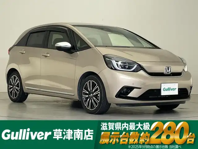 ホンダ フィット e:HEVリュクス 滋賀県 2022(令4)年 1.9万km ゴールド 純正9インチナビ/【Bluetooth/CD/DVD/フルセグTV】/ハーフレザーシート/バックカメラ/追従クルーズコントロール/クリアランスソナー/LEDヘッドライト/オートマチックハイビーム/前後ドライブレコーダー/D/Nシートヒーター/ステアリングヒーター/ビルトインETC/電動パーキングブレーキ/オートブレーキホールド/純正フロアマット/プッシュスタート/スマートキー/ステアリングリモコン