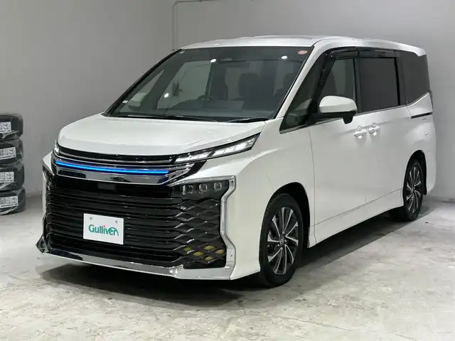 トヨタ ヴォクシー ハイブリッド S－Z 宮城県 2023(令5)年 6.5万km ホワイトパールクリスタルシャイン モデリスタシグネチャーイルミグリル/トヨタセーフティセンス/・プリクラッシュセーフティ/・レーンディパーチャーアラート/・プロアクティブドライビングアシスト/・パーキングサポートブレーキ/・クリアランスソナー/・ロードサインアシスト/・レーダークルーズコントロール/純正10.5インチディスプレイ/・ナビ/フルセグTV/BT/CD/DVD/HDMI/・バックカメラ/・ETC2.0/純正14型有機EL後席ディスプレイ/パワーバックドア/両側パワースライドドア/電子パーキング/・オートホールド/AC100V/革巻きステアリング/・ステアリングリモコン/・ステアリングヒーター/ハーフレザーシート/・シートヒーター(運転席/助手席/後席)/・オットマン/プッシュスタート/・スマートキー/・スペアキー/3眼LEDヘッドライト/・オートライト/・オートマチックハイビーム/電動格納ミラー/純正フロアマット/ドアバイザー