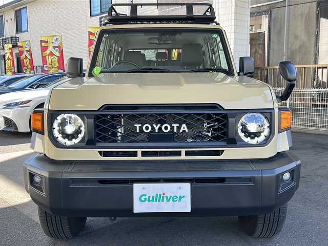 トヨタ ランドクルーザー AX 京都府 2024(令6)年 1.7万km ベージュ トヨタセーフティセンス　/イクリプス７型ＳＤナビ(AVN-LBS01)/Bluetooth　/USB入力端子/バックカメラ内蔵ルームミラー　/ディーゼル　/ターボ付　/４ＷＤ　/GIGEARオフロードアルミルーフラック　/ＤＡＣ　/ＰＣＳ　/ＬＤＡ　/ＲＳＡ　/コンビウッドハンドル　/純正デフロック/LEDヘッドライト/フロントフォグランプ/オートライト/オートマチックハイビーム/ダウンヒルアシストコントロール