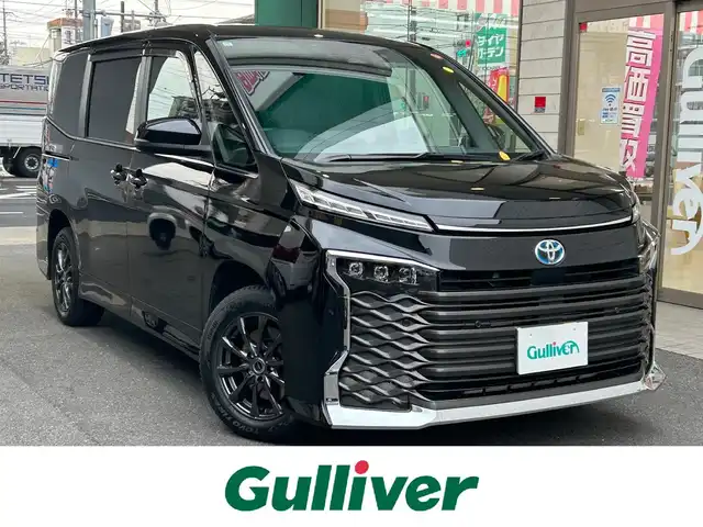 トヨタ ヴォクシー ハイブリッド S－Z 愛知県 2022(令4)年 4.9万km アティチュードブラックマイカ ワンオーナー/ディスプレイオーディオプラス〈MOP〉/・10.5インチディスプレイ／車載メモリナビ/・DVD／Bluetooth／地デジTV/・USB／HDMI／Apple Car Play／Android Auto/・ビルトインETC2.0/プロジェクター式LEDヘッドライト〈MOP〉/両側パワースライドドア/純正14.1型有機ELフリップダウンモニター/合皮＆ファブリックコンビシート/前席シートヒーター/2列目アームレスト付キャプテンシート/・充電用USBタイプC端子付折畳式サイドテーブル/社外16インチAW〈純正16インチAW積込〉/TOYOTA SAFETY SENSE/・プリクラッシュセーフティ/・レーントレーシングアシスト/・レーンディパーチャーアラート/・レーダークルーズコントロール/・オートマチックハイビーム/・ロードサインアシスト/・プロアクティブドライビングアシスト/ブラインドスポットモニター〈MOP〉/・安心降車アシスト/・アドバンスドドライブ/・フロントクロストラフィックアラート/・レーンチェンジアシスト/前後方パーキングサポートブレーキ/スマートキー