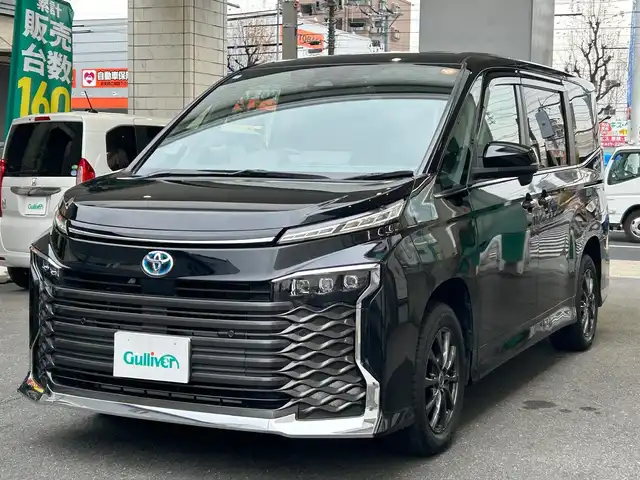 トヨタ ヴォクシー ハイブリッド S－Z 愛知県 2022(令4)年 4.9万km アティチュードブラックマイカ ワンオーナー/ディスプレイオーディオプラス〈MOP〉/・10.5インチディスプレイ／車載メモリナビ/・DVD／Bluetooth／地デジTV/・USB／HDMI／Apple Car Play／Android Auto/・ビルトインETC2.0/プロジェクター式LEDヘッドライト〈MOP〉/両側パワースライドドア/純正14.1型有機ELフリップダウンモニター/合皮＆ファブリックコンビシート/前席シートヒーター/2列目アームレスト付キャプテンシート/・充電用USBタイプC端子付折畳式サイドテーブル/社外16インチAW〈純正16インチAW積込〉/TOYOTA SAFETY SENSE/・プリクラッシュセーフティ/・レーントレーシングアシスト/・レーンディパーチャーアラート/・レーダークルーズコントロール/・オートマチックハイビーム/・ロードサインアシスト/・プロアクティブドライビングアシスト/ブラインドスポットモニター〈MOP〉/・安心降車アシスト/・アドバンスドドライブ/・フロントクロストラフィックアラート/・レーンチェンジアシスト/前後方パーキングサポートブレーキ/スマートキー