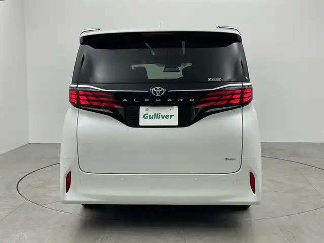 トヨタ アルファードハイブリット Z 愛知県 2024(令6)年 1.7万km プラチナホワイトパールマイカ 左右独立ムーンルーフ/13.2型有機EL後席ディスプレイ/14インチHDディスプレイオーディオ/(フルセグTV/BT/AM/FM)/合皮シート/前席＋二席目シートヒーター/前席＋二席目シートベンチレーション/全自動サンシェード/前後ドライブレコーダー/3眼LEDヘッドライト/ユニバーサルステップ/デジタルインナーミラー/トヨタセーフティセンス/・レーントレーシングアシスト/・プリクラッシュセーフティ/・ヘッドアップディスプレイ/・オートマチックハイビーム/・ブラインドスポットモニター/・クリアランスソナー/・パーキングサポートブレーキ/・アダクティブクルーズコントロール/ETC2.0/電動リアゲート/両側パワースライドドア/純正18インチAW/AC100V充電ソケット