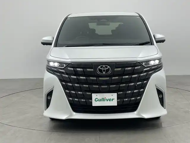 トヨタ アルファードハイブリット Z 愛知県 2024(令6)年 1.7万km プラチナホワイトパールマイカ 左右独立ムーンルーフ/13.2型有機EL後席ディスプレイ/14インチHDディスプレイオーディオ/(フルセグTV/BT/AM/FM)/合皮シート/前席＋二席目シートヒーター/前席＋二席目シートベンチレーション/全自動サンシェード/前後ドライブレコーダー/3眼LEDヘッドライト/ユニバーサルステップ/デジタルインナーミラー/トヨタセーフティセンス/・レーントレーシングアシスト/・プリクラッシュセーフティ/・ヘッドアップディスプレイ/・オートマチックハイビーム/・ブラインドスポットモニター/・クリアランスソナー/・パーキングサポートブレーキ/・アダクティブクルーズコントロール/ETC2.0/電動リアゲート/両側パワースライドドア/純正18インチAW/AC100V充電ソケット