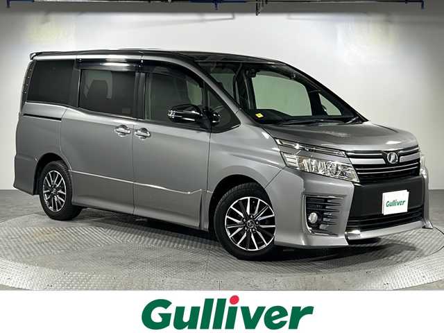 トヨタ ヴォクシー ZS 煌 沖縄県 2015(平27)年 8.4万km アイスチタニウムマイカメタリック 県外仕入　/純正９インチナビ/フルセグTV，Bluetooth，ラジオ，ＣＤ，ＤＶＤ　/７人乗り　/両側パワースライドドア/アルパインフリップダウン　/レザー調シートカバー　/ビルトインＥＴＣ　/ドライブレコーダー　/ライト付きハンディーミラー/デュアルエアコン/革巻きステアリング/純正ドアバイザー　/フロアマット/オートライト/LEDヘッドライト/フォグランプ/スペアキー/プッシュスタート