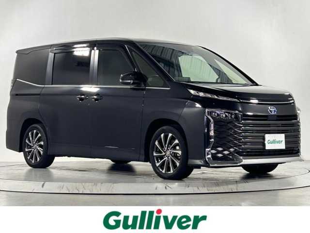 トヨタ ヴォクシー ハイブリッド S－Z 熊本県 2023(令5)年 2.9万km グリッターブラックガラスフレーク 純正10.5インチナビ/CD/DVD/フルセグTV/Bluetooth/純正14インチフリップダウンモニター/両側パワースライドドア/トヨタセーフティセンス/プリクラッシュセーフティ/レーンディパーチャーアラート/クリアランスソナー/パーキングサポートブレーキ/ロードサインアシスト/プロアクティブドライビングアシスト/快適利便パッケージ/ユニバーサルステップ/ハーフレザーシート/シートヒーター/オットマン/１００V充電/追従付きクルーズコントロール/オートハイビーム/前後ドライブレコーダー/ビルトインETC2.0/フロアマット/純正ドアバイザー/純正17インチアルミホイール