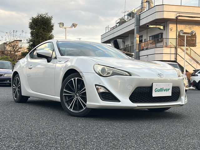 トヨタ ８６ GT 東京都 2012(平24)年 8.9万km サテンホワイトパール 純正ナビ（NHZN-W61G）/・Bluetooth/TV/CD/DVD/USB/バックカメラ/ドライブレコーダー（VREC-DZ300）/横滑り防止装置/盗難防止装置/17インチ純正アルミホイール/電動格納ミラー/rosso modello製マフラー/KUHL RACING スワンネックGTウィング/社外テールランプ/オートエアコン/オートライト/パドルシフト
