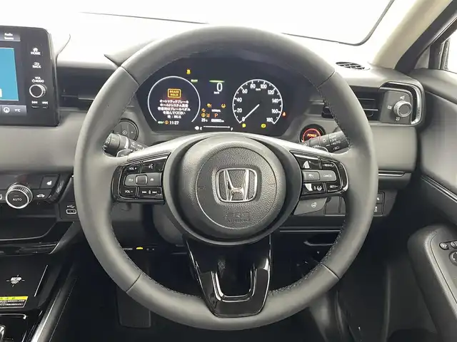 ホンダ ヴェゼル ハイブリッド e:HEV Z 熊本県 2025(令7)年 0.1万km未満 プラチナホワイトパール 登録済未使用車/純正ナビ（ＡｐｐｌＣａｒＰｌａｙ・ＡｎｄｒｏｉｄＡｕｔｏ・フルセグ・ＢＴ・ＵＳＢ）　/バックカメラ　/ビルトインＥＴＣ　/ホンダセンシング/・衝突軽減ブレーキ/・誤発進抑制機能/・後方誤発進抑制機能/・近距離衝突軽減ブレーキ/・歩行者事故低減ステアリング/・路外逸脱制御機能/・アダブティブクルーズコントロール/・渋滞運転支援機能/・先行車発進お知らせ/・標識認識システム/・ブラインドスポットモニター/・車線維持支援システム/・オートハイビーム/横滑り防止/ダウンヒルアシスト/置くだけ充電/前席シートヒーター/ステアリングヒーター/パワーバックドア/パドルシフト/ブレーキホールド/ハーフレザーシート/純正１８インチAW/フロントシーケンシャルウインカー/オートライト/LEDヘッドライト/フォグライト/スマートキー/プッシュスタート/スペアキー1本/保証書/取扱説明書