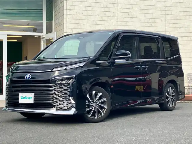 トヨタ ヴォクシー ハイブリッド S－Z 静岡県 2023(令5)年 5.9万km グリッターブラックガラスフレーク 純正10.5インチナビ(CD/DVD/BT/フルセグ)/14インチ後席モニター(V14T-R72R)/純正ETC2.0/ドライブレコーダー前後+車内/エンジンスタートボタン/パワーステアリング/パワーウィンドウ/アイドリングストップ/100V充電/スマートキー/Wオートエアコン/レーダークルーズコントロール/USB入力端子/バックカメラ/三列シート/純正フロアマット/ハーフレザーシート/D席N席シートヒーター/両側パワースライドドア/純正17インチアルミホイール/ABS/横滑り防止装置/コーナーセンサー前後/レーンキープアシスト/オートライト/オートマチックハイビーム/LEDヘッドライト/W+サイドエアバック/衝突軽減システム/HDMI接続