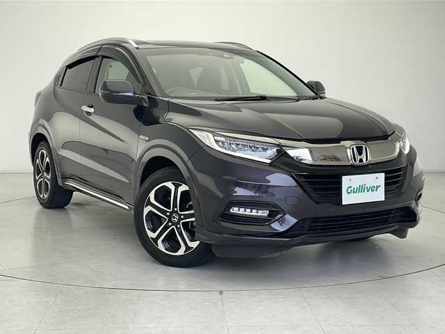 ホンダ ヴェゼル ハイブリッド Z ホンダセンシング 千葉県 2018(平30)年 5.9万km ルーセブラックM ホンダセンシング/衝突被害軽減装置/レーンキープアシスト/レーダークルーズコントロール/先行車発進お知らせ/路外逸脱抑制システム/横滑り防止装置/リアクティブフォースペダル/標識認識/ディーラー純正ナビ/　CD DVD BT フルセグTV/バックカメラ/ホールド機能付き電子パーキングブレーキ/前後ドライブレコーダー/ビルトインETC/ハーフレザーシート/シートヒーター/トノカバー/LEDヘッドライト/オートライト/フォグランプ/電動格納ウィンカーミラー/ドアバイザー/純正フロアマット/PWオールオート/ルーフレール/革巻きステアリング/ステアリングスイッチ/パドルシフト/プッシュスタート/スマートキー
