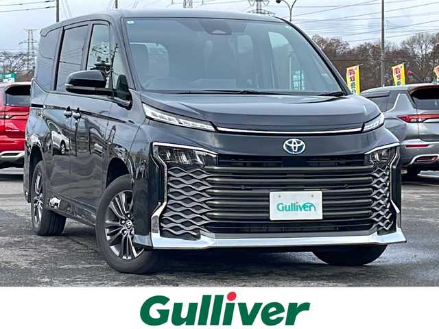 トヨタ ヴォクシー ハイブリッド S－G 道央・札幌 2025(令7)年 1.1万km グリッターブラックガラスフレーク ４WD/寒冷地仕様/純正ディスプレイオーディオ（ナビ付）/AM/FM/BT/トヨタセーフティセンス/プリクラッシュセーフティ/横滑り防止装置/レーダークルーズコントロール/レーンキープアシスト/パーキングアシスト/プロアクティブドライビングアシスト/パーキングサポートブレーキ/ロードサインアシスト/クリアランスソナー/バックカメラ/ビルトインETC2.0/EVMODE/DRIVEMODE切替/ワイパーデアイサー/片側パワースライドドア/革巻きステアリング/ステアリングリモコン/電動パーキング/ブレーキホールド/プッシュスタート/スマートキー/LEDヘッドライト/オートライト/オートハイビーム/ヘッドライトレベライザー/電動格納ミラー/ウィンカーミラー/純正フロアマット/レンタカー登録