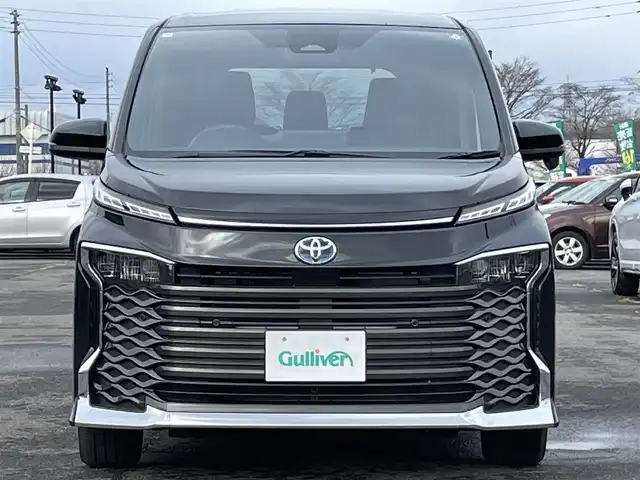 トヨタ ヴォクシー ハイブリッド S－G 道央・札幌 2025(令7)年 1.1万km グリッターブラックガラスフレーク ４WD/寒冷地仕様/純正ディスプレイオーディオ（ナビ付）/AM/FM/BT/トヨタセーフティセンス/プリクラッシュセーフティ/横滑り防止装置/レーダークルーズコントロール/レーンキープアシスト/パーキングアシスト/プロアクティブドライビングアシスト/パーキングサポートブレーキ/ロードサインアシスト/クリアランスソナー/バックカメラ/ビルトインETC2.0/EVMODE/DRIVEMODE切替/ワイパーデアイサー/片側パワースライドドア/革巻きステアリング/ステアリングリモコン/電動パーキング/ブレーキホールド/プッシュスタート/スマートキー/LEDヘッドライト/オートライト/オートハイビーム/ヘッドライトレベライザー/電動格納ミラー/ウィンカーミラー/純正フロアマット/レンタカー登録