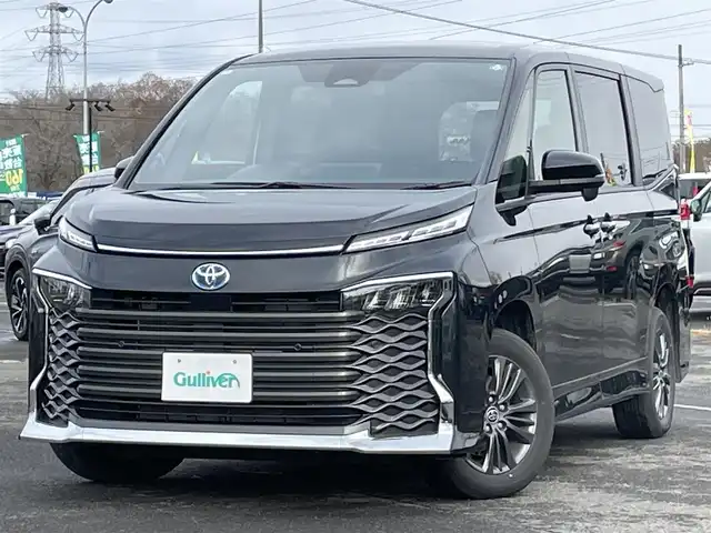 トヨタ ヴォクシー ハイブリッド S－G 道央・札幌 2025(令7)年 1.1万km グリッターブラックガラスフレーク ４WD/寒冷地仕様/純正ディスプレイオーディオ（ナビ付）/AM/FM/BT/トヨタセーフティセンス/プリクラッシュセーフティ/横滑り防止装置/レーダークルーズコントロール/レーンキープアシスト/パーキングアシスト/プロアクティブドライビングアシスト/パーキングサポートブレーキ/ロードサインアシスト/クリアランスソナー/バックカメラ/ビルトインETC2.0/EVMODE/DRIVEMODE切替/ワイパーデアイサー/片側パワースライドドア/革巻きステアリング/ステアリングリモコン/電動パーキング/ブレーキホールド/プッシュスタート/スマートキー/LEDヘッドライト/オートライト/オートハイビーム/ヘッドライトレベライザー/電動格納ミラー/ウィンカーミラー/純正フロアマット/レンタカー登録
